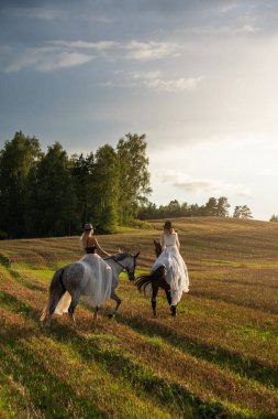 Güneş Işığı Tarlası 'nda Atlara Binen Şık Giyimli İki Kadın.