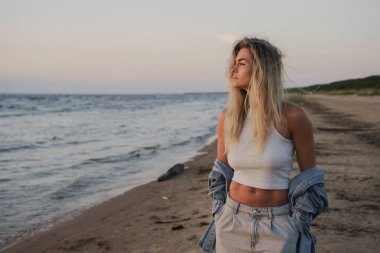 Genç Tarz Kadını Sahilde Günbatımının tadını çıkarıyor.