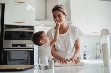 Mutlu anne ve oğlu modern bir mutfakta birlikte yemek pişiriyorlar.. 