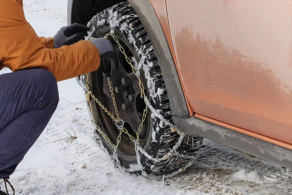 Şoför kışın arabasının direksiyonuna zincir takar. Off-road ve kötü hava için araç gereçleri.