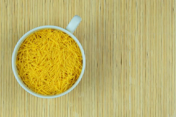 Pasta in bowl on a straw background. Vegetarian organic product. Vintage view. Top view. Copy space.