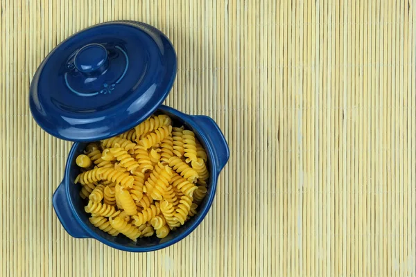 Pasta in blue bowl on a straw background. Vegetarian organic product. Vintage view. Top view. Copy space.