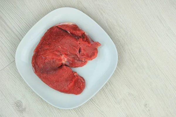 Beef pulp in plate in white wood background. Raw meat for cooking.