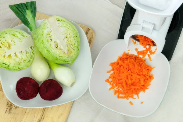 菜刀里的胡萝卜放在厨房桌子上 切碎的胡萝卜掉进了一个碗里 家庭自制健康食品 免版税图库照片