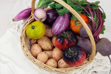 Çeşitli sebzelerle dolu bir sepet. Patates, pancar, domates, soğan, patlıcan. Ülke biçimi. 