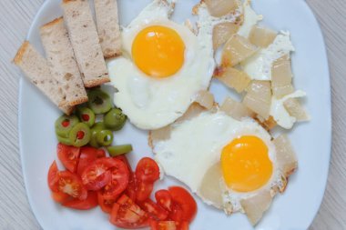 Yağda yumurta, domates ve yeşil zeytinli bir tabak. Ev yapımı kahvaltı. Ev yemeği mi? Üst görünüm.