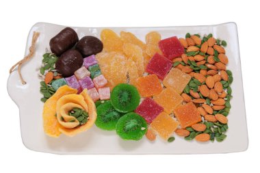 Marmalade, candied fruit, mango, kiwi, nuts, seeds, chocolate candies and Turkish delight in a plate. Variety of sweet desserts in plate.