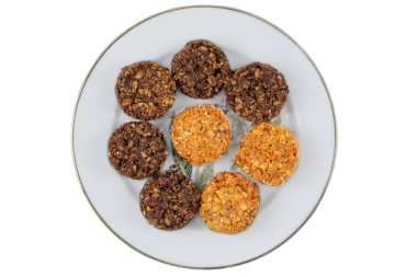 Beyaz arka planda izole edilmiş seramik tabakta çeşitli pastalar. Sarı ve kahverengi romantik bisküvi. Üst görünüm.