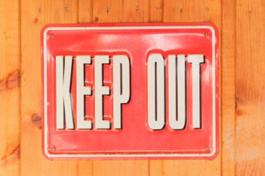 Uzak dur. Ahşap zemin üzerinde yazı olan metal bir tabela. Metal uyarı işareti. Eski nesne.