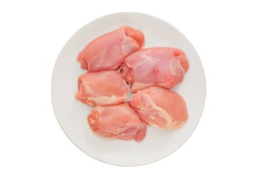 Kemiksiz tavuk butları tabakta. Beyaz arka planda izole edilmiş. Pişirmek için çiğ tavuk eti. Evde yemek pişirmek. Üst görünüm.