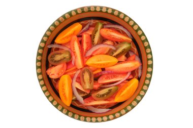 Üst Manzara. Kırsal kasede kırmızı dilimlenmiş domates. Kil tabakadaki domatesler beyaz arka planda izole edilir. Sulu domates.. 