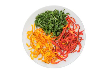 Beyaz arka planda izole edilmiş seramik tabakta kurutulmuş tatlı biber ve maydanoz. Çeşitli sebzeler. Yolculuk için dondurulmuş sebze. Üst görünüm.