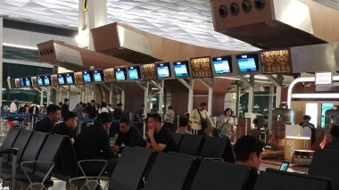 Jakarta, Endonezya - 28 Nisan 2024: Uçak yolcuları Soekarno Hatta Havalimanı bekleme salonunda oturuyorlar.