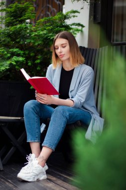 Confident beautiful girl with a notebook on the terrace. Business style. Psychologist