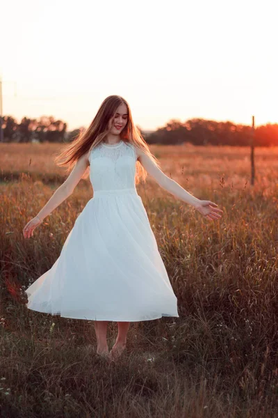 美しい可愛い女の子が白いドレスで日没の野原で踊っています ハッピーな女性 コンセプト ブライド — ストック写真