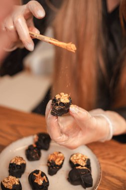 Kadın pastacı, cadılar bayramı için siyah kafatasları şeklinde şekeri altınla süslüyor. Cadılar Bayramı için şeker yaratma süreci