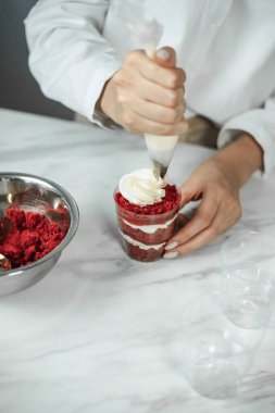 Process of creating red velvet trifle. Confectioner at work