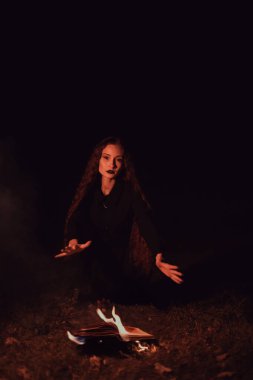 Cadı yanan bir kitabın üzerine büyü yapıyor, mistisizm, Cadılar Bayramı, gotik kadın.