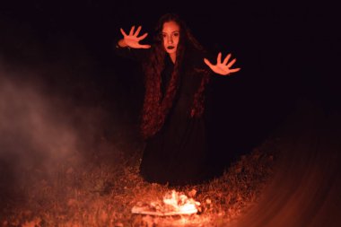 Cadı yanan bir kitabın üzerine büyü yapıyor, mistisizm, Cadılar Bayramı, gotik kadın.