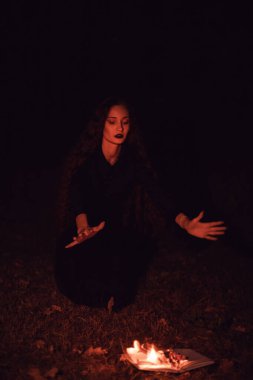 Cadı yanan bir kitabın üzerine büyü yapıyor, mistisizm, Cadılar Bayramı, gotik kadın.