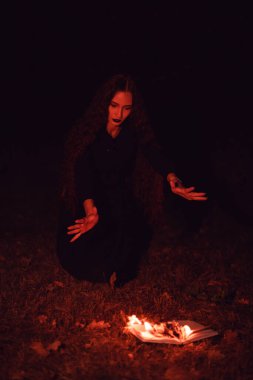 Cadı yanan bir kitabın üzerine büyü yapıyor, mistisizm, Cadılar Bayramı, gotik kadın.