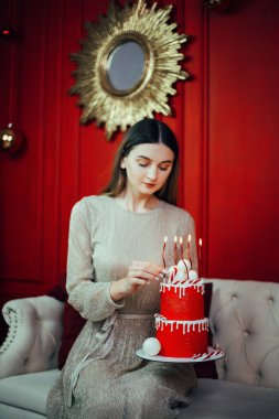 Kutlama kırmızı bir pasta ve mumlarla özel bir durum için dekore edilmiş rahat bir odada.