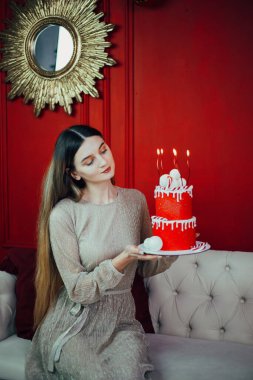 Kutlama kırmızı bir pasta ve mumlarla özel bir durum için dekore edilmiş rahat bir odada.