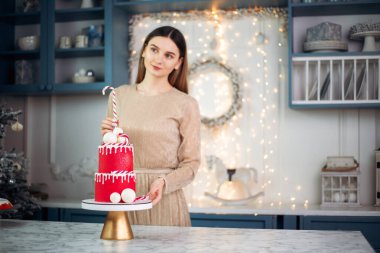 Süslü kırmızı pasta ve Noel şekeri ile süslenmiş sıcak aydınlatılmış mutfakta, kış dekoruyla süslenmiş şekerlemeci. Şenlikli Noel 