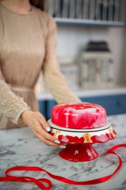 Lezzetli bir yeni yıl pastası parlak bir mutfakta kırmızı bir standa konuyor.