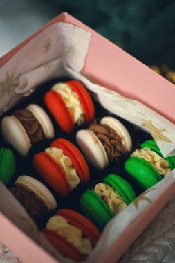 Kış kutlamaları sırasında bir Noel ağacının altında pembe bir kutuda düzenlenmiş renkli badem kurabiyesi seçimi.