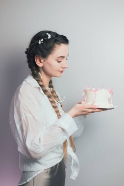 Şekerci elinde pembe kurdeleli, gülümseyen bir doğum günü pastası tutuyor.