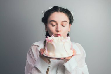 Güzel dekore edilmiş bir pastaya neşeyle öpücük yollayan genç bir bayanla özel bir kutlama.