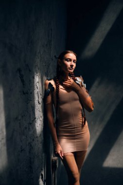 Bir kadın fotoğraf çekimi sırasında loş bir odada kelebeklerle duvarın yanında duruyor.