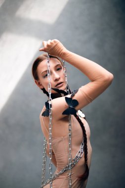 Dansçı, gün ışığında stüdyoda açık renk kıyafetler giyerken sanatsal poz vermiş.