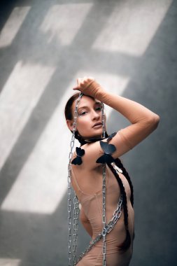 Dansçı, gün ışığında stüdyoda açık renk kıyafetler giyerken sanatsal poz vermiş.