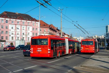 BRATISLAVA, SLOVAKIA - 21 Mart 2022. Otobüs SOR NB 18 City # 2235 ve troleybüs Skoda # 31TR SOR # 6804 Bratislava sokaklarında yolcularla birlikte.