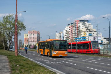 BRATISLAVA, SLOVAKIA - 29 Mart 2022. Irisbus Citelis otobüsü 12M # 1033 ve Skoda 29T2 # 7430 numaralı tramvay Bratislava sokaklarında yolcularla yolculuk ediyor..