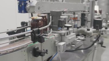 Yoğun bir fabrikada, otomatik makineler cam kavanozları bal ile doldurur, verimliliği vurgular..