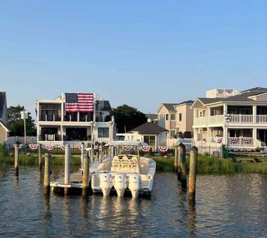Çiçeklerle süslenmiş, dekoratif balkonlu pembe deniz kenarı binası. Kıyı yaşamı, Akdeniz cazibesi.