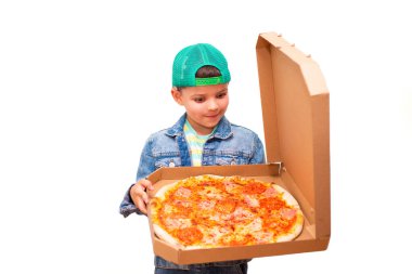 Yedi yaşında, yeşil şapkalı, açık yeşil gözlüklü, modaya uygun bir çocuk arka planda izole edilmiş bir pizza kutusu tutuyor..