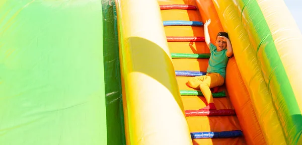 색상의 소년은 공원에서 화려한 슬라이드의 계단에 미소와 태양으로부터 손으로 스톡 이미지