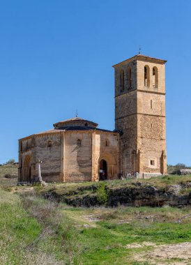 Ancient Templar church near Segovia, Spain. Its historic stone tower rises from the rocky outcrop, the fortified architecture standing sharply against a clear blue sky