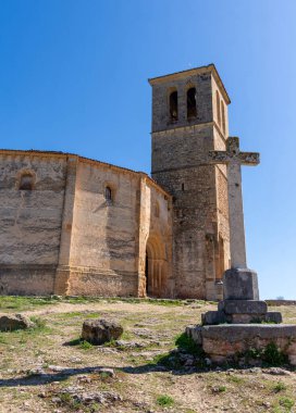 Ancient Templar church near Segovia, Spain. Its historic stone tower rises from the rocky outcrop, the fortified architecture standing sharply against a clear blue sky