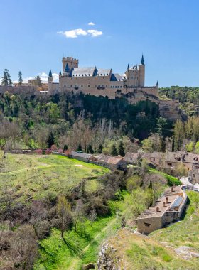 The Alczar of Segovia, Spain (c. 1120): This majestic royal fortress with distinctive slate spires stands on a rocky crag against a clear blue sky, a Spanish medieval landmark