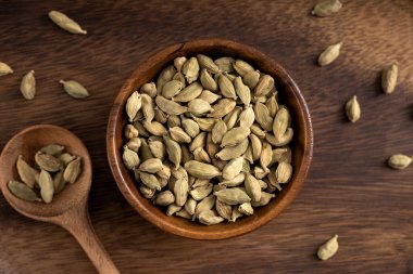 Kardamon tohum kasesi. Ahşap zemine yayılmış kardamon tohumları. Yukarı görüntü çekimi.