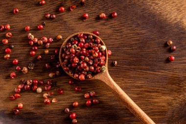 Red pepper seeds on wooden rustic spoon. Up view studio shoot on wooden background. clipart