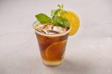 Taze limonlu buzlu çay. Gri arkaplanda tek kullanımlık bardak.