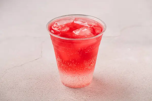 Strawberry soda on plastic cup. Cold red drink. Isolated on gray backgr