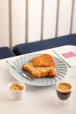 Kahvaltı masası, kruvasan ve kahve bir restoran masasında servis edilir.