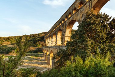 Three tiers of ancient Roman  Pont Du Gard aqueduct reflecting in Gardon river in Southern France